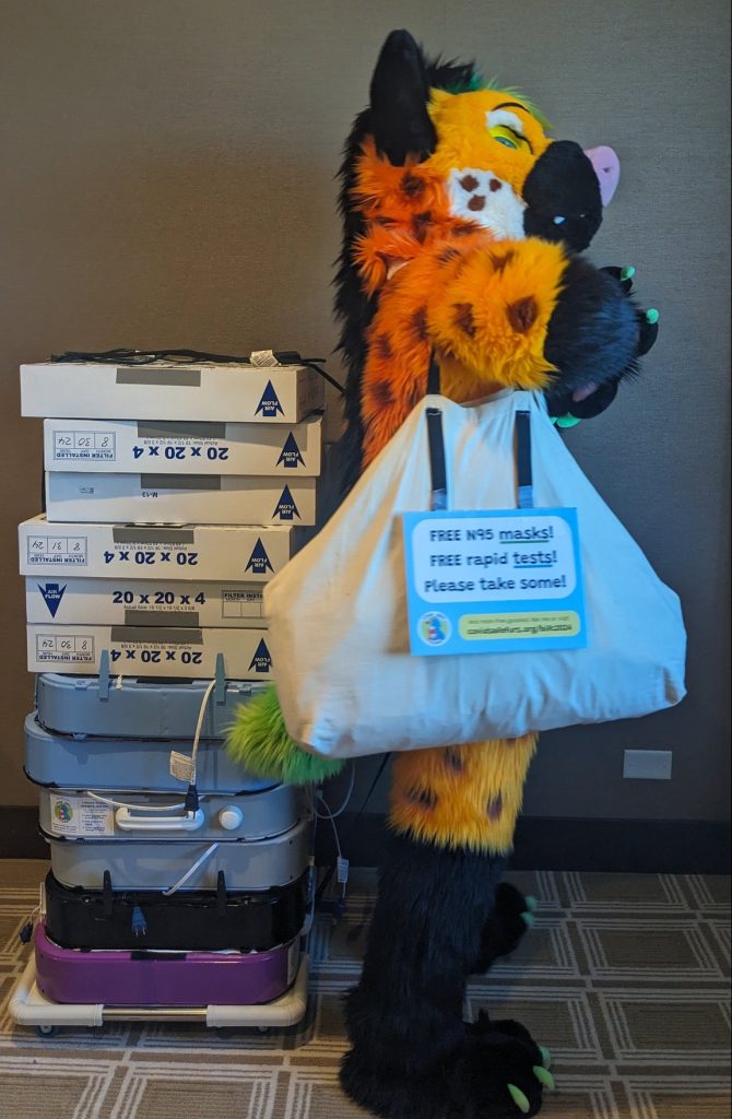 Hyena fursuiter with a bag of masks and tests and a stack of air filters.